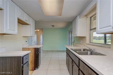 Kitchen with a sink, white cabinetry, light counte