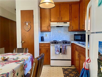 Kitchen with range, backsplash, white fridge, and light tile floors