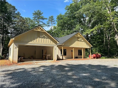 View of front of property featuring board and batten siding, a garage, a shingled roof, and gravel driveway