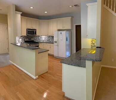 Kitchen with a peninsula, dark stone countertops, appliances with stainless steel finishes, and recessed lighting
