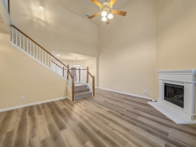 Unfurnished living room featuring light wood-style flooring, a high ceiling, a chandelier, a fireplace with raised hearth, and stairs