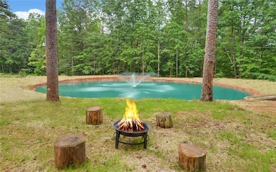 View of yard with an outdoor fire pit, a water view, and a forest view