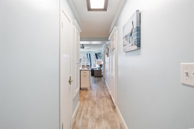 Hallway with crown molding and light hardwood / wo