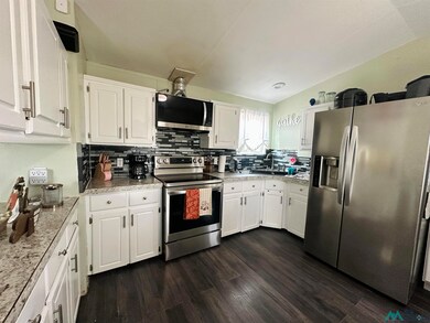 Kitchen with appliances with stainless steel finishes, white cabinets, decorative backsplash, dark wood finished floors, and light countertops