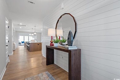 Hallway with light wood-style floors, recessed lighting, a chandelier, and wooden walls