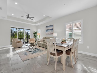 Dining space featuring healthy amount of natural light, a tray ceiling, recessed lighting, and a ceiling fan