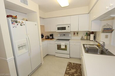 Kitchen with white appliances, light countertops, white cabinetry, and light tile patterned floors