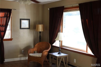 Living area featuring wood finished floors, baseboard heating, and ceiling fan