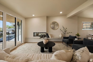 Living room with a wealth of natural light, wood finished floors, beamed ceiling, and recessed lighting