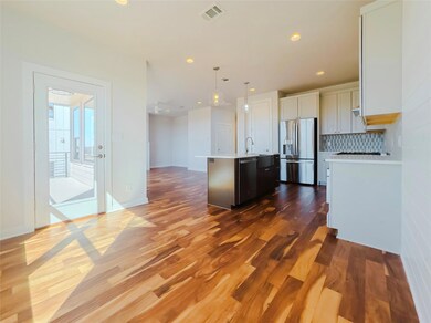 Kitchen featuring appliances with stainless steel finishes, hanging light fixtures, tasteful backsplash, an island with sink, and white cabinets