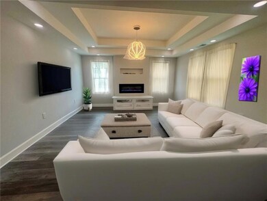Staged~ Living room area featuring a raised trey ceiling and dark wood finished floors