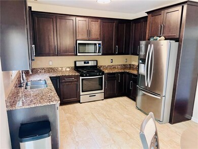 Spacious Kitchen with stainless steel appliances, granite countertops, and dark brown cabinetry.