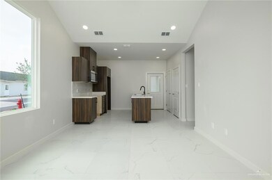 Unfurnished living room featuring baseboards, a sink, light marble finish flooring, recessed lighting, and plenty of natural light