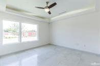 Unfurnished room featuring a tray ceiling and ceiling fan