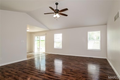 Spare room with healthy amount of natural light, ceiling fan, dark wood-style flooring, and high vaulted ceiling