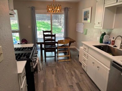 Kitchen with appliances with stainless steel finishes, white cabinetry, dark wood-style floors, decorative light fixtures, and a textured wall