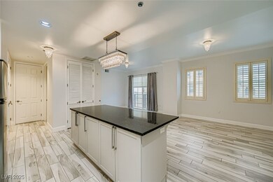 Kitchen with dark stone countertops, wood tiled floors, decorative light fixtures, white cabinetry, and a center island