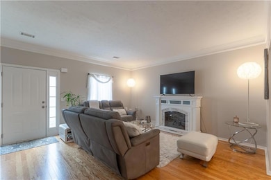 Living area with light wood finished floors, crown molding, a fireplace, and a textured ceiling