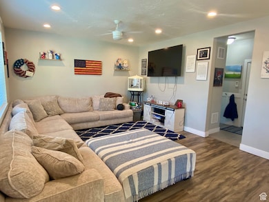 Living room with dark wood finished floors, a ceiling fan, recessed lighting, and a textured ceiling