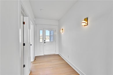 Doorway with baseboards and light wood-style floors