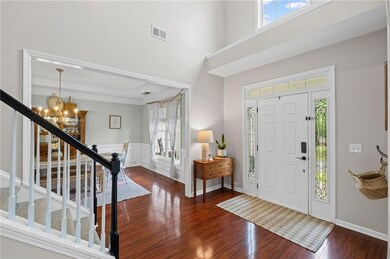 Entryway featuring a chandelier, healthy amount of natural light, wood finished floors, stairs, and a high ceiling