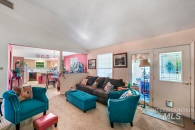 Carpeted living room featuring vaulted ceiling, a textured ceiling, and a chandelier