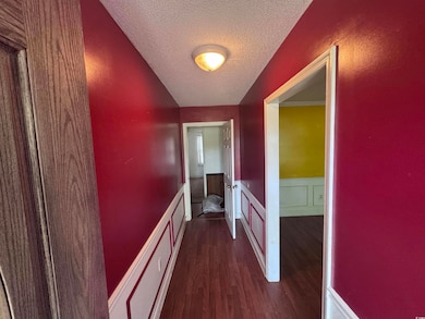 Corridor with a wainscoted wall, a textured ceilin