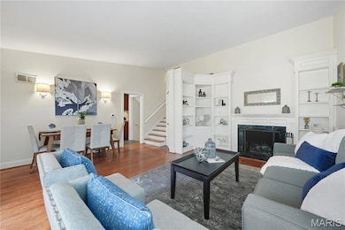 Living area with wood finished floors, a fireplace, and stairs