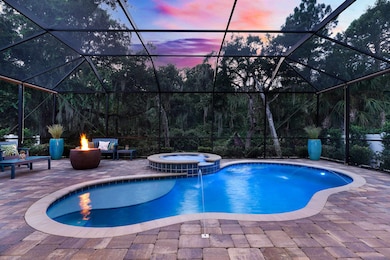 View of pool featuring glass enclosure, a pool with connected hot tub, a sunroom, and a patio area