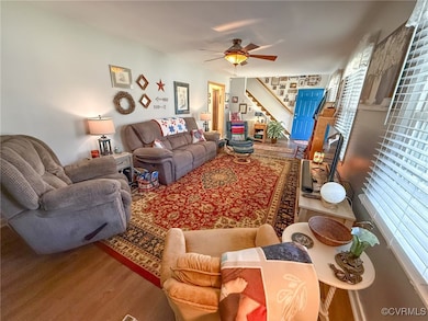 Living area with a ceiling fan, stairway, and wood