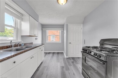 Kitchen with white cabinets, light hardwood floors, gas range, and plenty of natural light