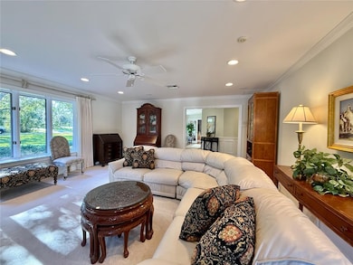 Living area featuring ornamental molding, recessed lighting, carpet, and a ceiling fan
