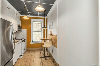 Kitchen featuring white cabinets, light wood-type flooring, decorative backsplash, and appliances with stainless steel finishes