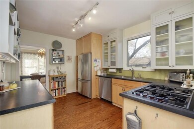 Kitchen featuring glass insert cabinets, dark countertops, dark wood-type flooring, and appliances with stainless steel finishes
