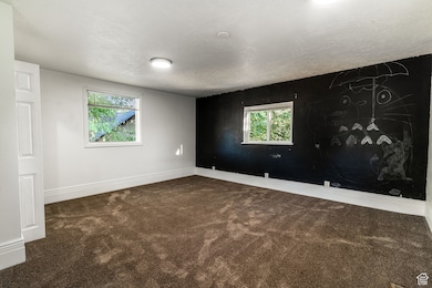 Unfurnished room with dark colored carpet and a textured ceiling