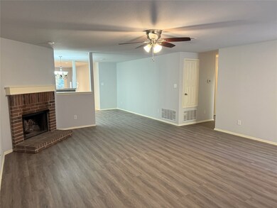 Unfurnished living room with a fireplace, dark wood finished floors, ceiling fan, and a chandelier