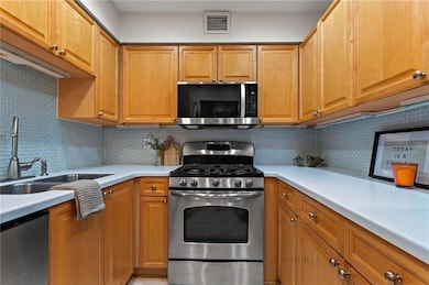 Kitchen with white granite countertops, blue tile backsplash and stainless steel appliances.