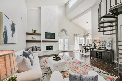 The family room is anchored by a floor-to-ceiling painted brick wood-burning fireplace accented by floating reclaimed wood shelving and an extended hearth. Adjacent to the fireplace, French doors overlook the backyard oasis.