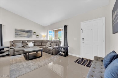 Tiled living area with vaulted ceiling and baseboa