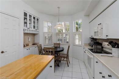Kitchen with white cabinetry, white appliances, ta