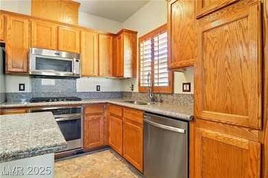 Kitchen featuring appliances with stainless steel finishes, brown cabinets, and dark stone countertops