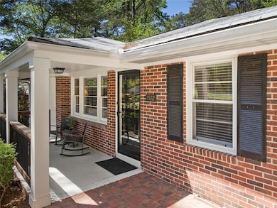 View of exterior entry featuring a porch and brick siding