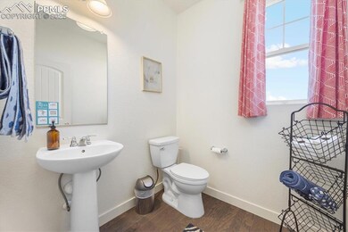 Bathroom with wood finished floors, toilet, basebo