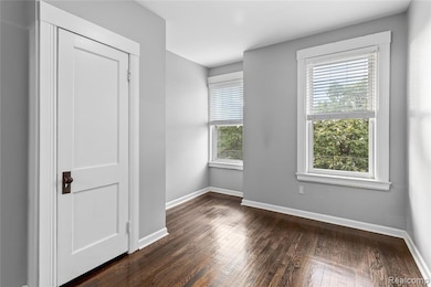 Empty room with plenty of natural light and dark wood-style flooring