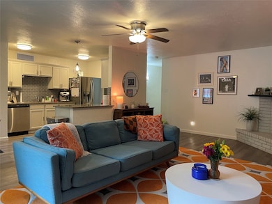 Living area with a textured ceiling, wood finished floors, and ceiling fan