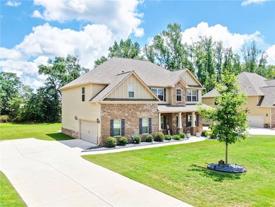 Craftsman-style house featuring board and batten siding, a front yard, a porch, brick siding, and a garage