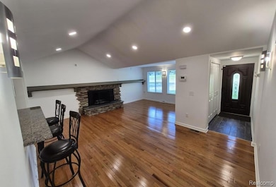 Unfurnished living room with dark wood-style flooring, a fireplace, lofted ceiling, and recessed lighting