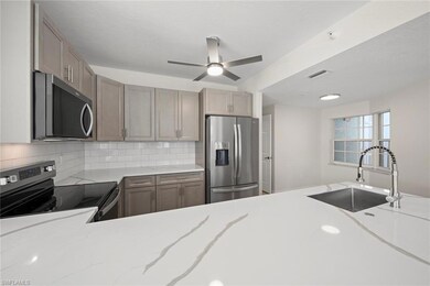Kitchen featuring stainless steel appliances, light stone countertops, decorative backsplash, and a ceiling fan