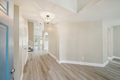 This is the view when entering the home. Interior features include an open entry area with access to the formal dining room at the right, updated vinyl plank flooring, fresh interior paint and arched doorway leading into the breakfast area and kitchen.