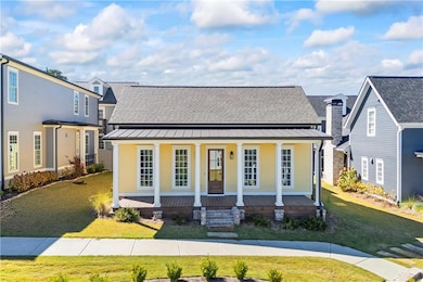 View of front facade with a porch, a front lawn, a standing seam roof, and a metal roof